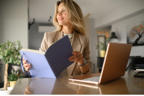 Une femme souriante travaillant sur un ordinateur, illustrant la transformation par la réécriture persuasive.