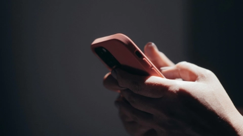 Gros plan sur les mains d’une personne utilisant un téléphone à la finition pêche.